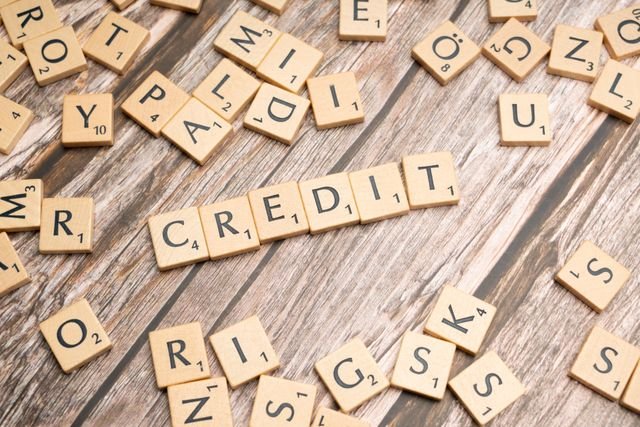 How to improve your credit score Wooden letter tiles arranged to spell 'CREDIT' on a rustic table background.